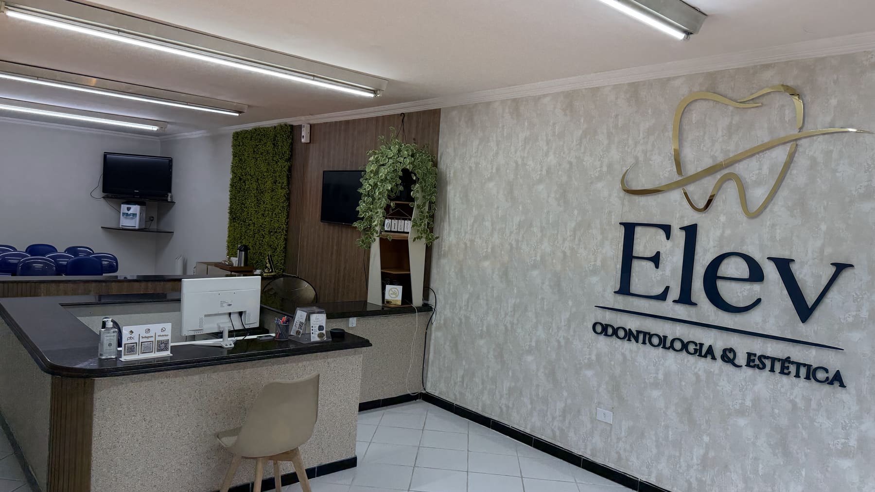 Recepção da Elev Odontologia e Estética, com o letreiro da marca na parede e o balcão de atendimento